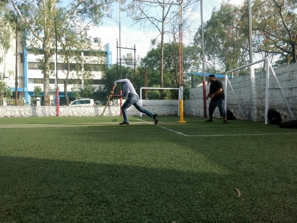 Two men playing cricket on a turf field.
